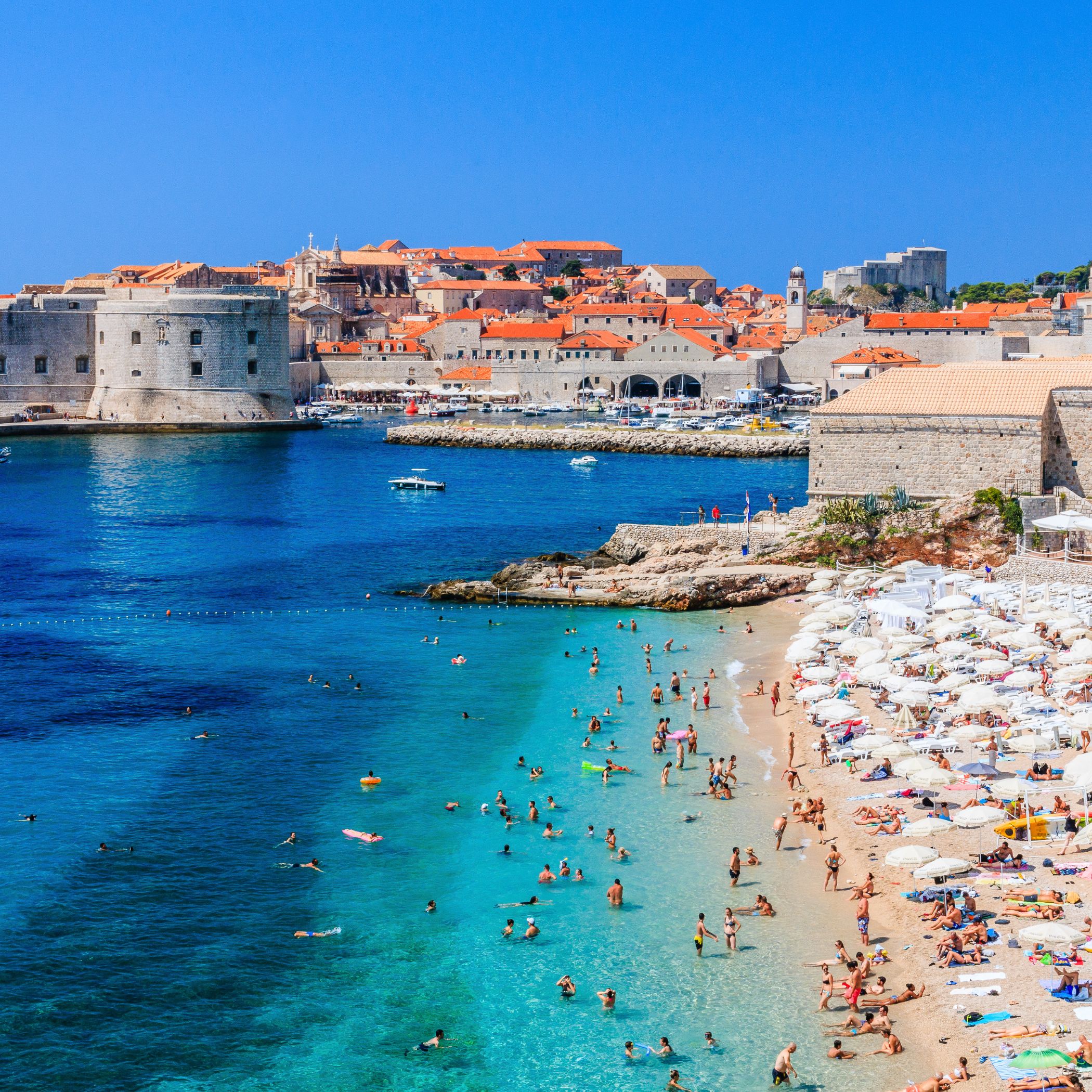 Aerial shot of a popular beach with buildings in the background, highlighting the coastal beauty near Dubrovnik 