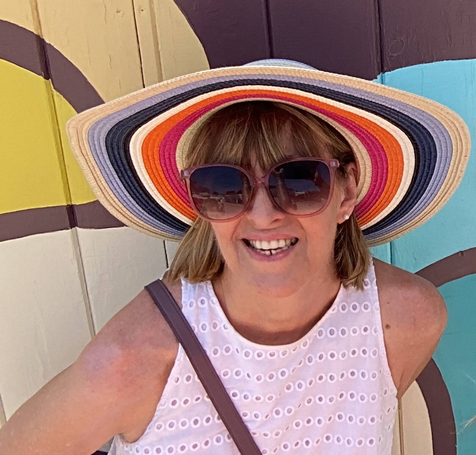 Sequel travel agent Julie wearing a large sun hat and enjoying a cruise