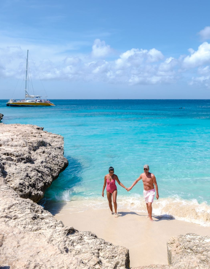 Couple celebrating a romantic milestone while walking hand in hand on the sand of a remote tropical beach 