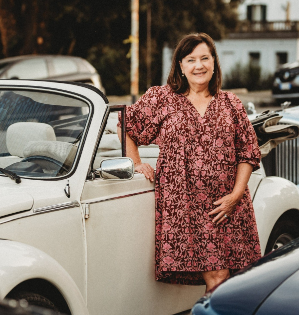 Sequel travel expert Maryneil is photographed at sunset in Europe, leaning against a classic car