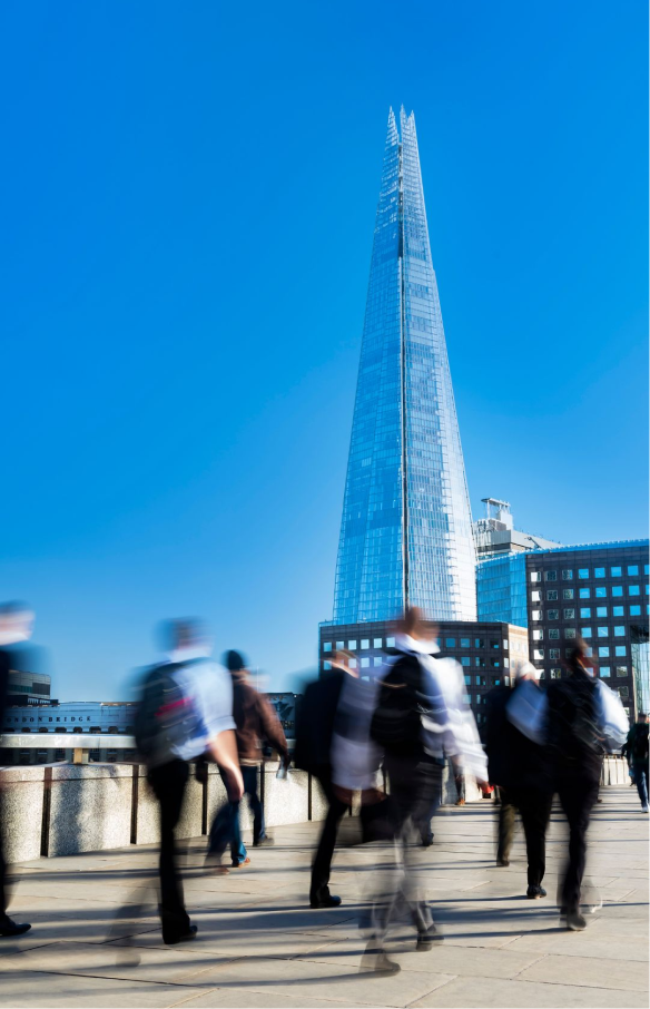 Blurred image of busy people walking, with a focus on a glass skyscraper in the background